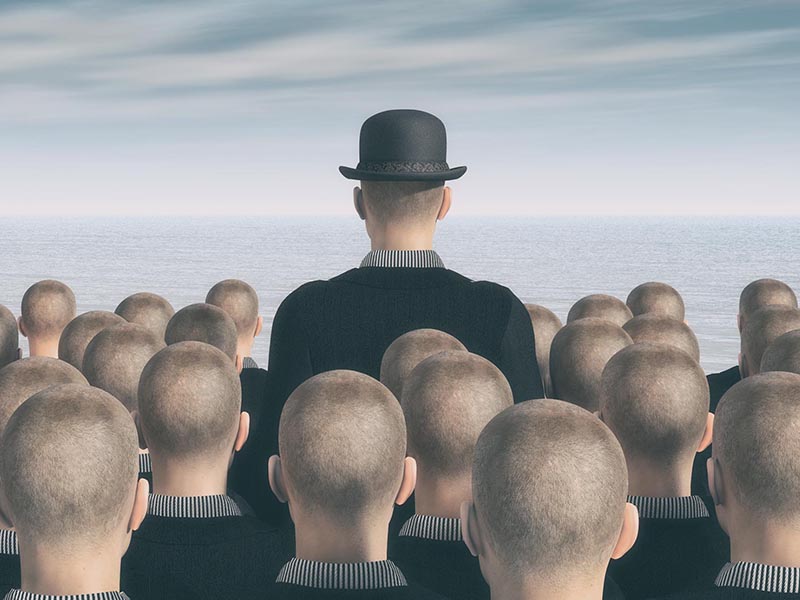 A man in a bowler hat stands out from a crowd of identical men, symbolizing the need for a competitive business website.